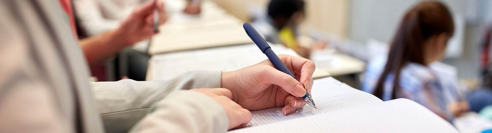 Close up of a person writing in a notebook.