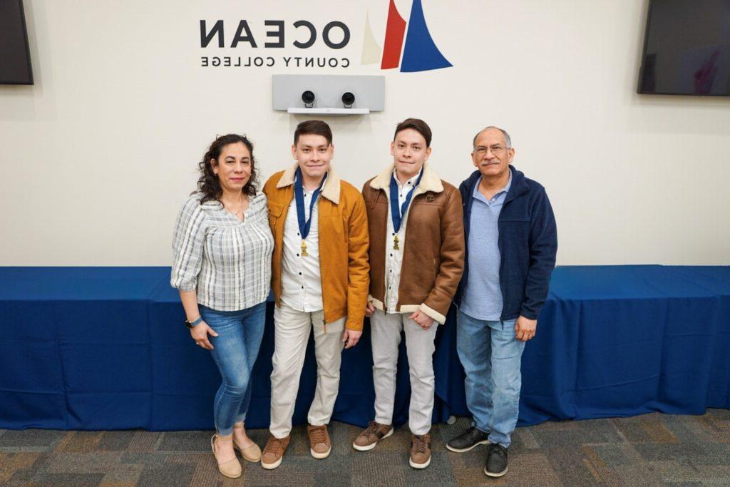 Twins with their medals posing with their parents.